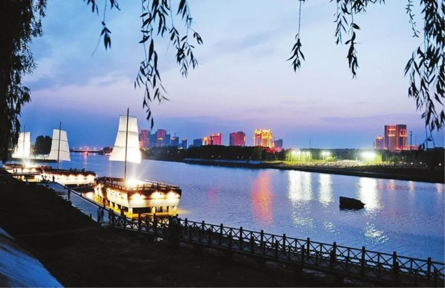 Hình nền điện thoại đẹp với thuyền buồm phát sáng trên sông, thành phố lung linh dưới bầu trời hoàng hôn